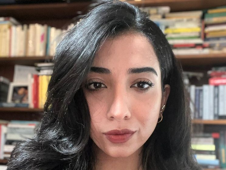 Il volto in primo piano di una giovane ragazza dagli occhi neri e i capelli neri lunghi e sciolti