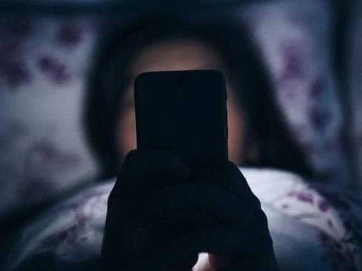 Una ragazzina davanti al suo smartphone in cameretta