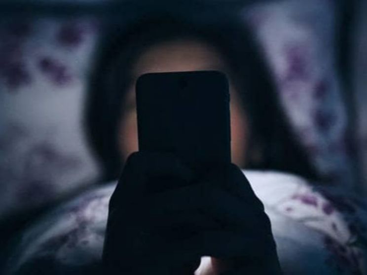 Una ragazzina davanti al suo smartphone in cameretta