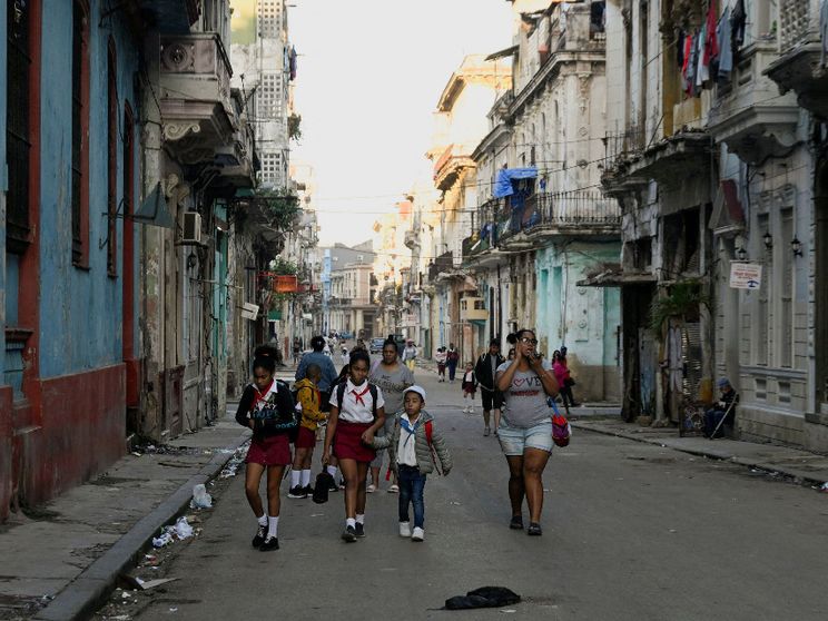 Un gruppo di bambini in uniforme scolastico cammina per il centro dell'Avana fra edifici malridotti per la mancanza di manutenzione