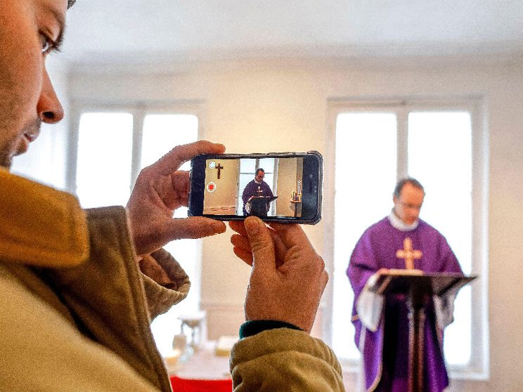 Un sacerdote ripreso con uno smartphone