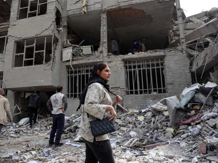 Una donna davanti a un edificio distrutto a Teheran