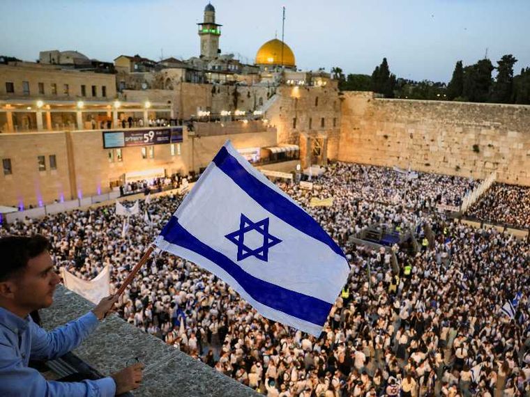 Un giovane nazionalista agita una bandiera israeliana da un balcone davanti alla folla radunata al Muro Occidentale di Gerusalemme