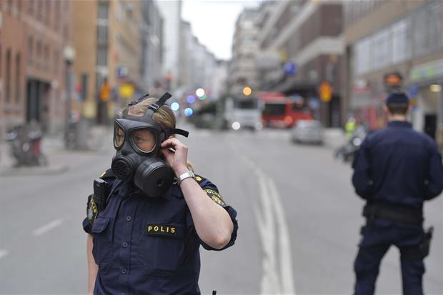 Poliziotti in strada a Stoccolma con la maschera antigas (Ansa)
