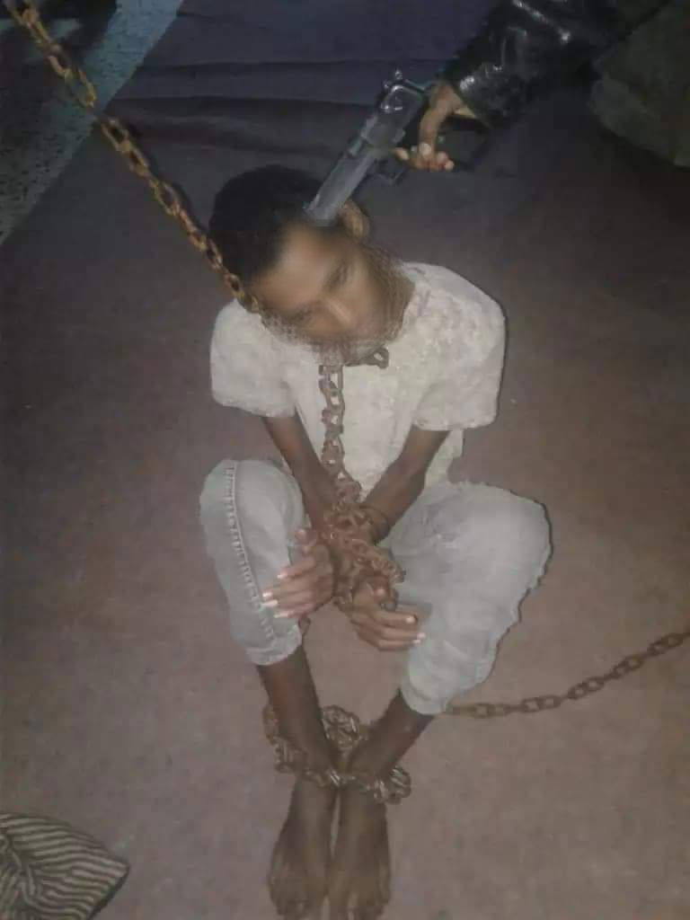 Un giovane eritreo minacciato con la pistola da un trafficante di esseri umani dopo esser stato ridotto in catene. Queste immagini vengono inviate dagli schiavisti ai parenti dei detenuti nel lager di Bani Walid per ricattarli Le pubblichiamo per documentare l’orrore che si consuma in quei campi libici