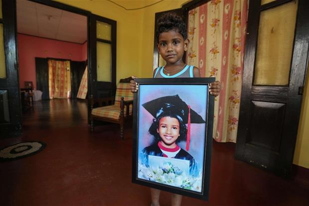 Bimbo con il ritratto della sorellina morta lo scorso anno a Colombo