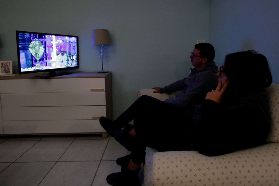 Una famiglia mentre segue in diretta tv la preghiera e la benedizione Urbi et Orbi di papa Francesco