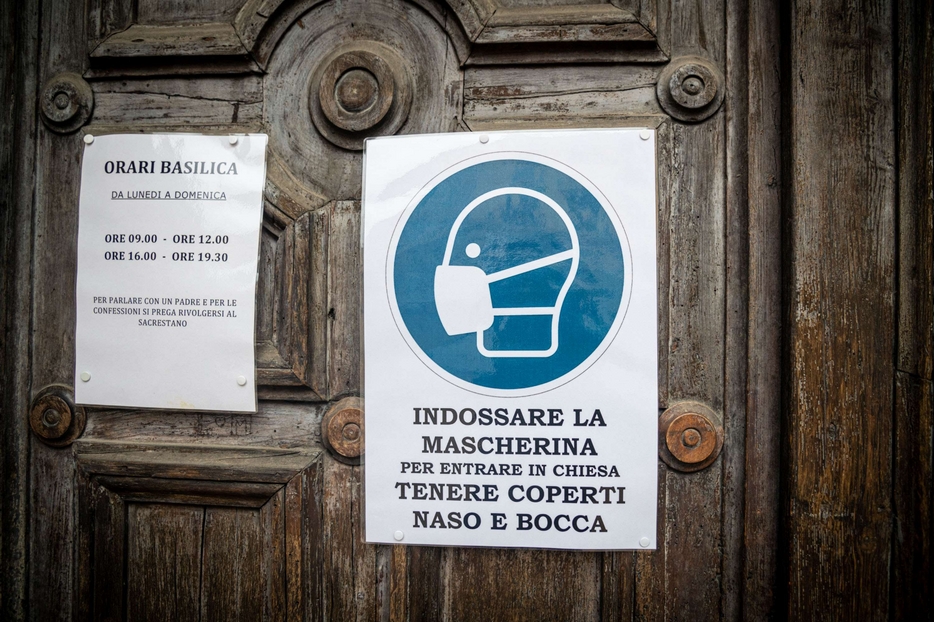 All'ingresso di una chiesa il cartello che indica l'obbligo della mascherina