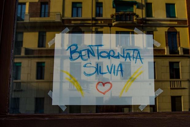Un cartello di benvenuto sul portone dell'abitazione di Silvia Romano, a Milano