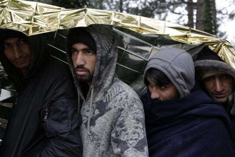 Alcuni profughi si proteggono con una coperta termica lungo la rotta balcanica