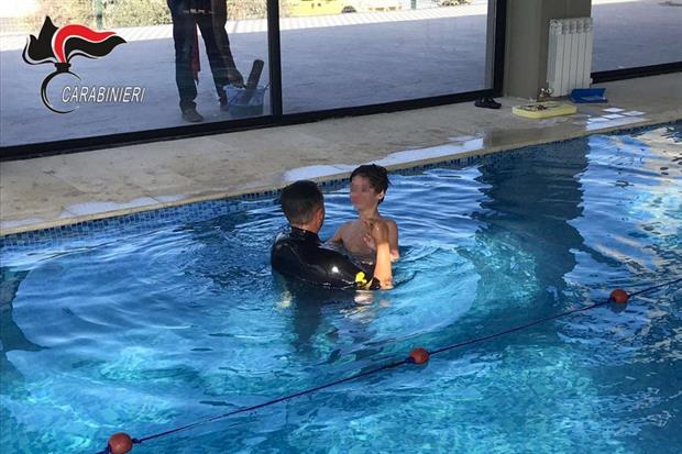 Un carabiniere istruttore affianca un bambino durante le attività formative in acqua