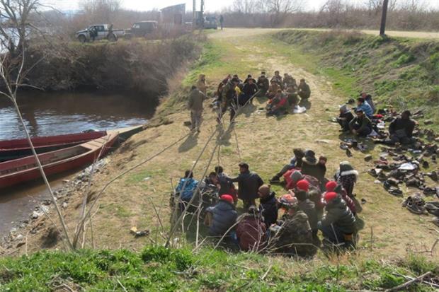 Un gruppo di profughi bloccato sul fiume Evros dai 'cacciatori' che hanno tolto loro le scarpe, ammassate tutto su un lato, in attesa che arrivi la polizia a portarli nei centri di detenzione