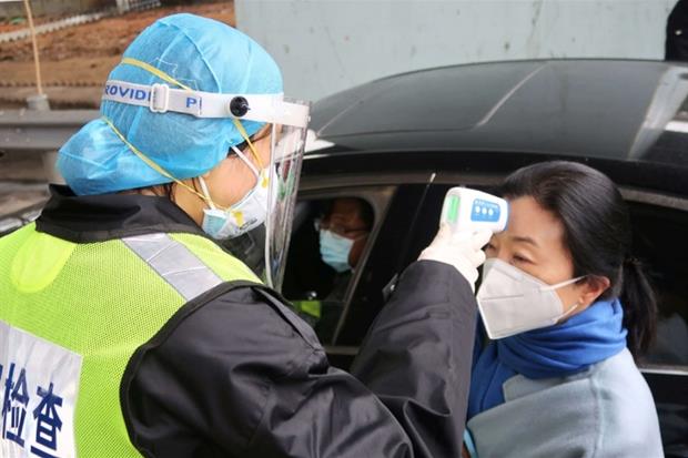 Un agente controlla la temperatura al casello di un'autostrada a Xianning