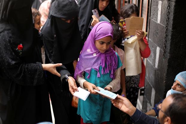 Una bambina riceve un buono alimentare a Sanaa (luglio 2020)