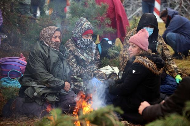 Migranti intorno al fuoco in attesa di tentare il passaggio dalla Bielorussia alla Polonia
