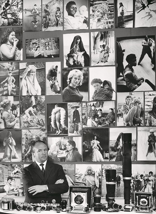 Mario De Biasi alla sua scrivania nella redazione di 'Epoca'. In primo piano l'attrezzatura fotografica, alle spalle ritratti femminili raccolti nei cinque continenti, Milano, anni ’ 60