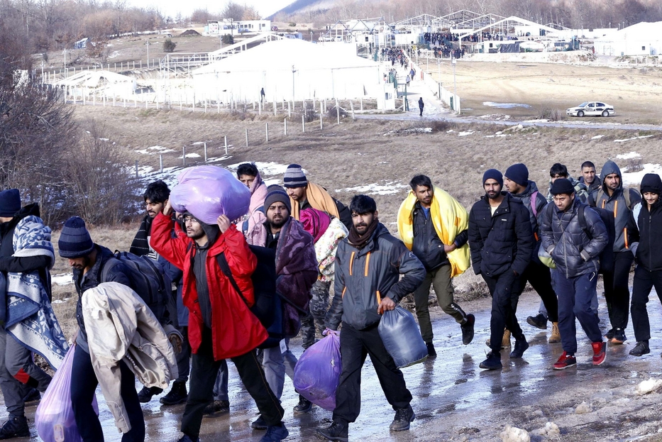 Migranti si allontanano dopo l'incendio che ha distrutto il campo Lipa, a Bihac (Bosnia)