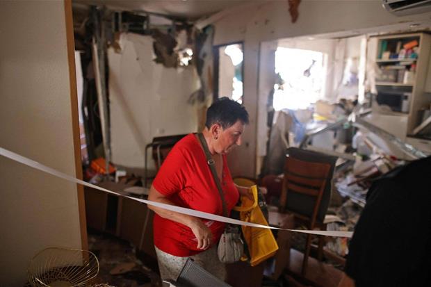 Una donna di Ashdod, nel sud di Israele, lascia la sua casa distrutta da un razzo sparato da Gaza