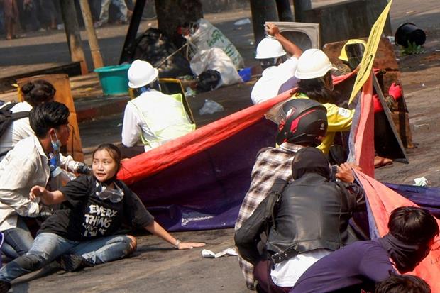 Giovani attivisti della rivolta birmana si abbassano a terra per sfuggire ai colpi della polizia