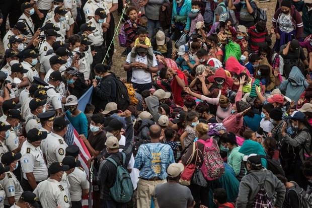 I migranti partiti dall'Ecuador in preghiera davanti alla polizia nel villaggio di Vado Hondo, in Guatemala, che ha bloccato il passaggio della carovana