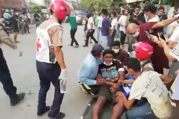 Un manifestante ferito dalla polizia a Mandalay viene soccorso