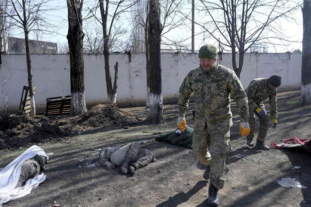Un soldato ucraino cammina a fianco a un commilitone ucciso nel bombardamento di Mikolaiv