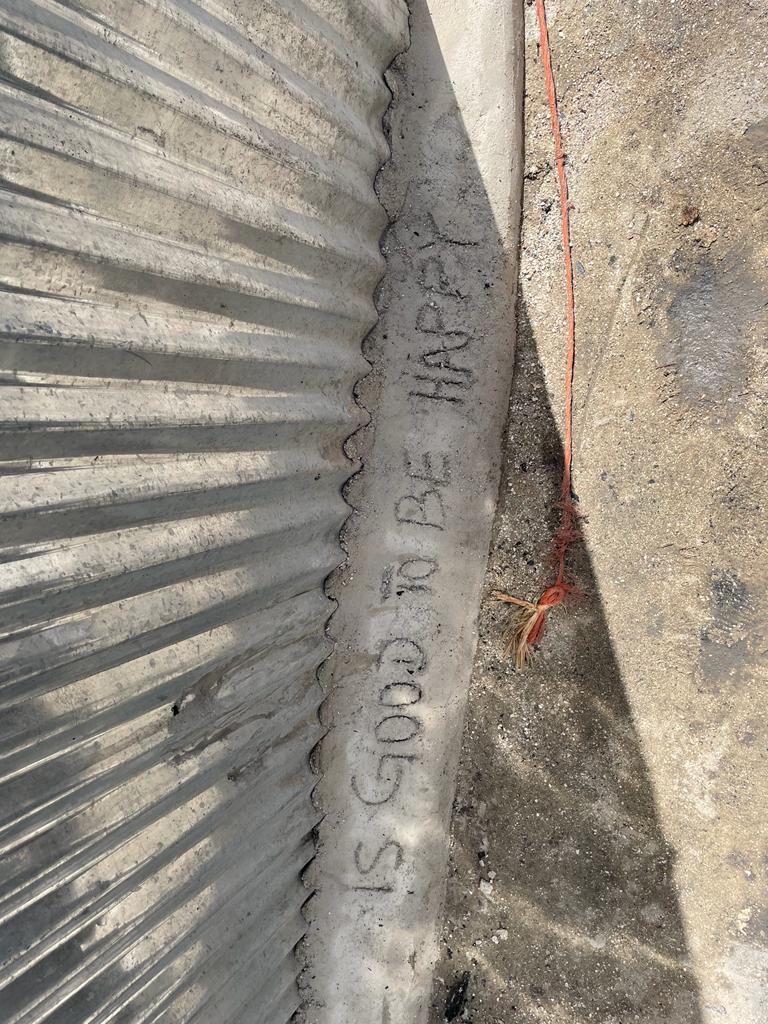 Sul bordo in cemento della baracca a fianco di quella bruciata un immigrato aveva inciso la frase “Is good to be happy”, “E’ bello essere felici”