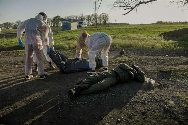 Sotto, un tecnico forense davanti  ai resti diUna fossa comune scoperta nel villaggio di Vilkhivka, nella regione di Kharkiv