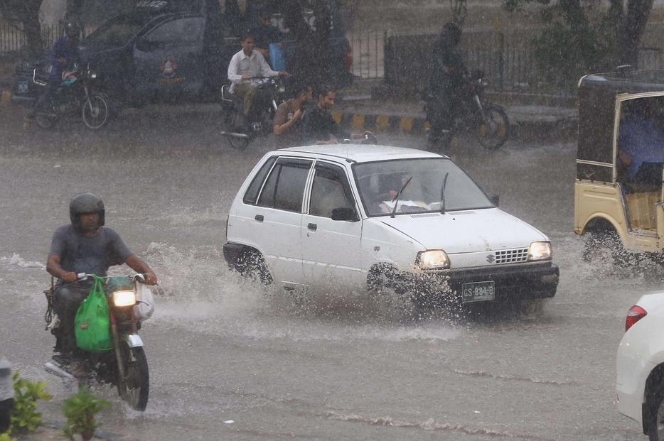Auto e pedoni a galla in una strada inondata di Karachi in Pakistan