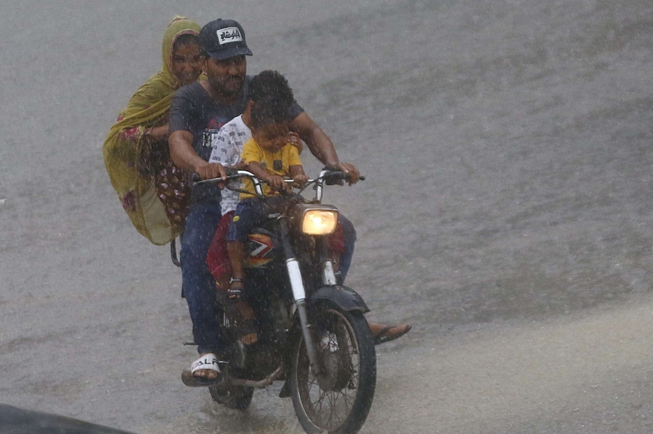 Una famiglia in motocicletta sotto la pioggia dei monsoni a Karachi in Pakistan
