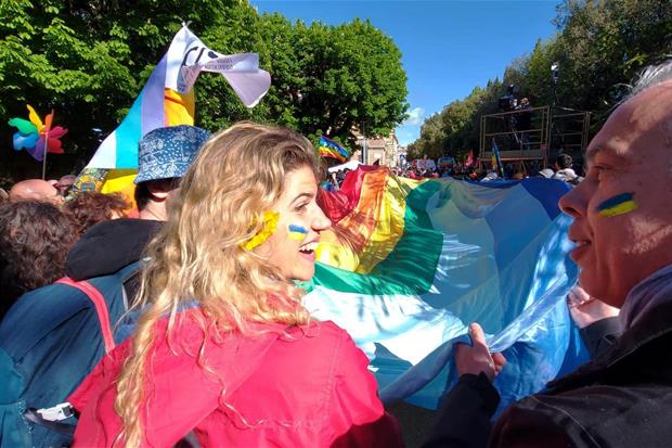 Dietro allo striscione arcobaleno, il giallo e il blu dell'Ucraina sul volto di molti manifestanti