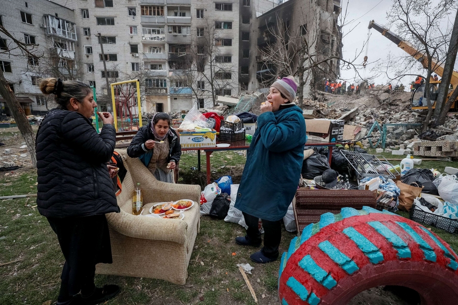 Alcuni sfollati ucraini davanti alle loro case bombardate
