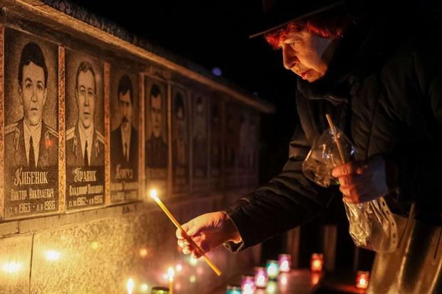 Nel 36esimo anniversario del disastro nucleare di Chernobyl una donna accende delle candele al Memoriale