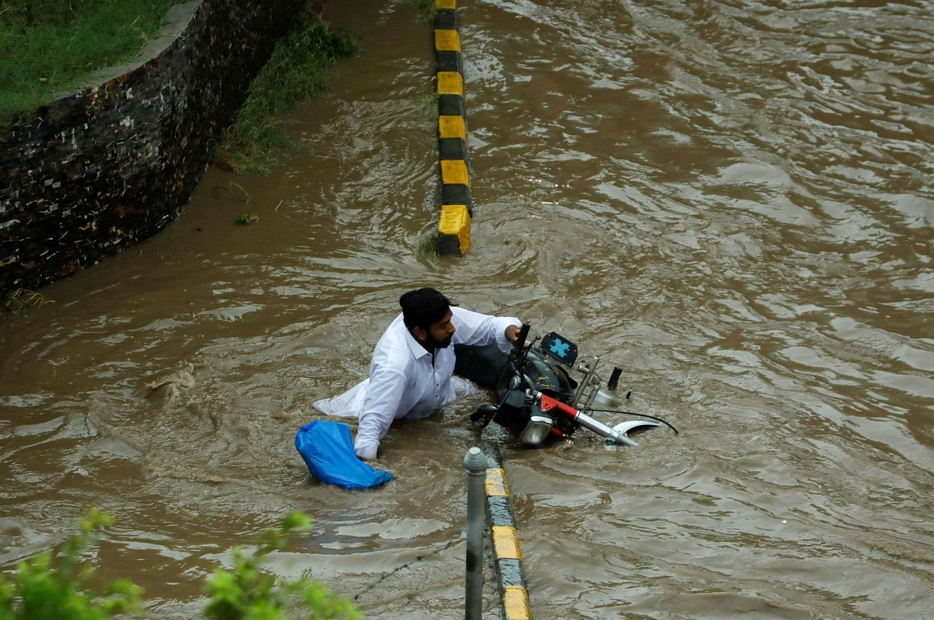 Un uomo cade dalla motocicletta mentre attraversa una strada allagata dai monsoni