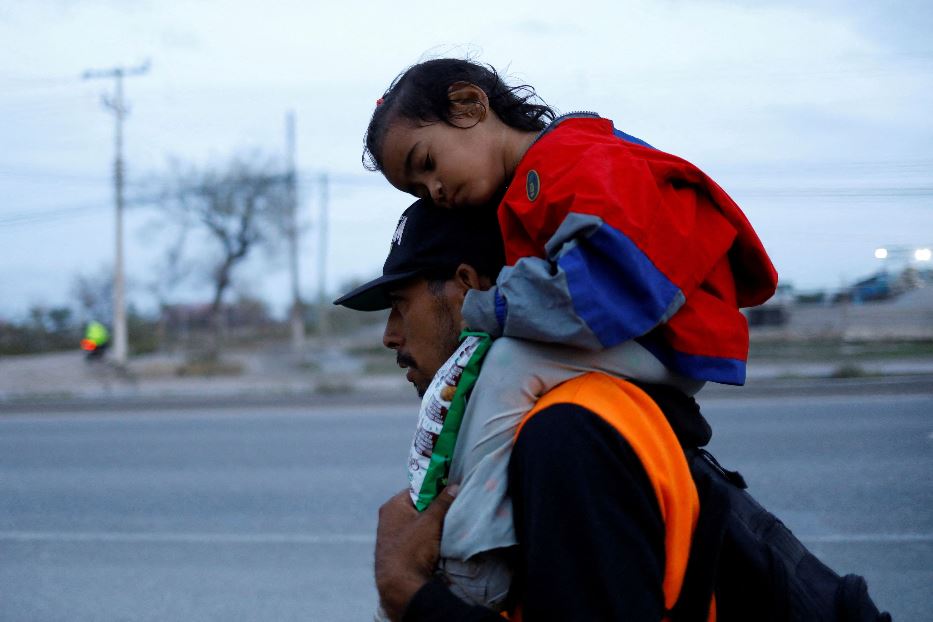 Padre con la bimba sulle spalle a Piedras Negras sul confine tra Messico e Usa