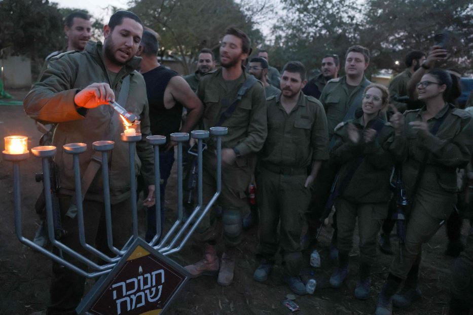 Un soldato accende la prima luce di Hanukkah in una postazione militare sul fronte di Gaza