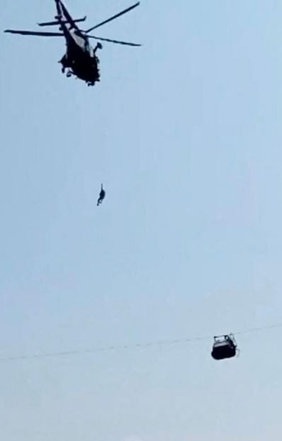 Un militare si cala dall'elicottero per portare in salvo i passeggeri bloccati nella cabina sospesa nel vuoto