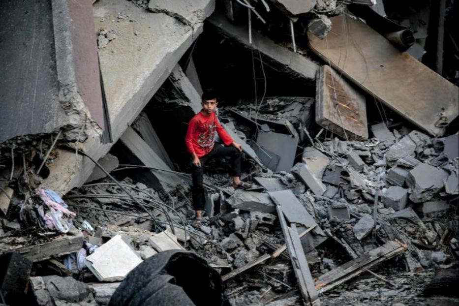 Un ragazzo palestinese tra le macerie di un edificio crollato dopo un attacco israeliano a Gaza