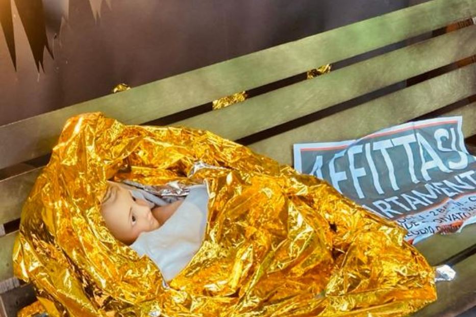 Il Bambino Gesù avvolto in un telo termico e deposto su una panchina, nel presepe di Casa della Carità