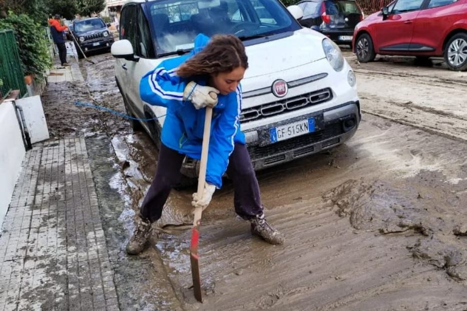 Una ragazza mentre spala il fango in una via di Prato
