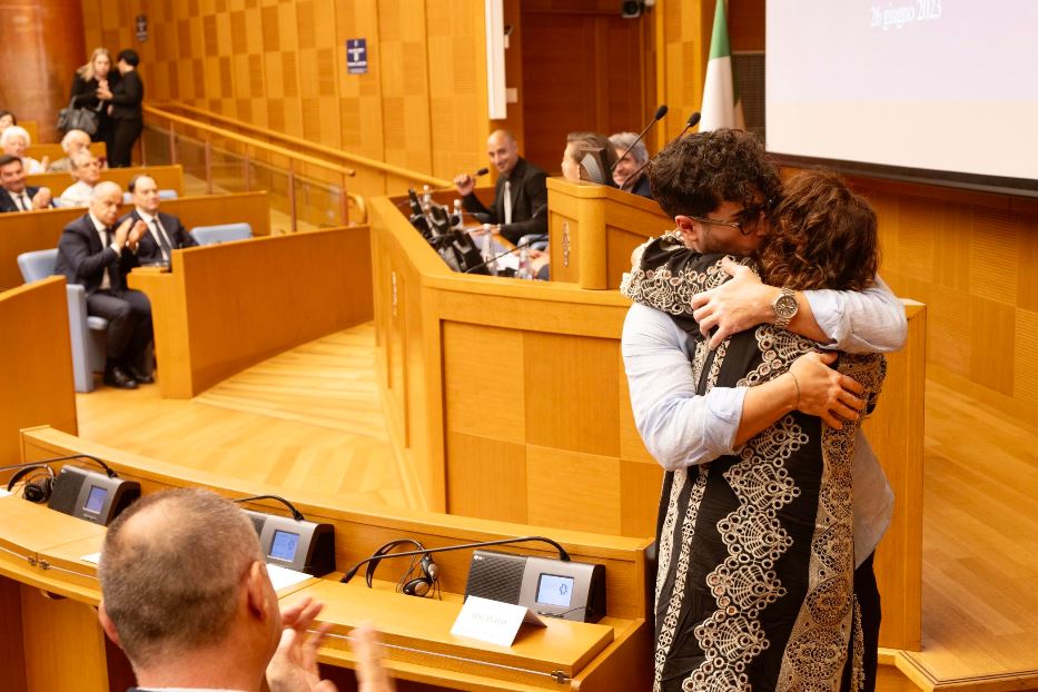 Madre e figlio si abbracciano dopo una testimonianza, tra gli applausi della platea