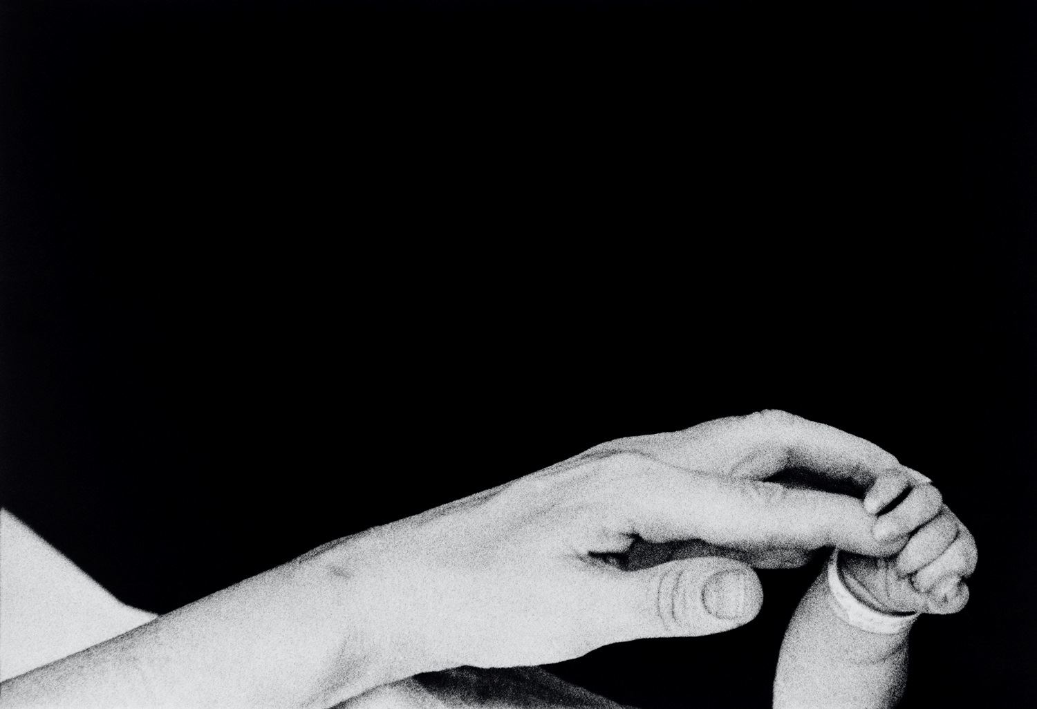 In mostra a Forlì, Musei di San Domenico, 'Eve Arnold. L’opera, 1950-1980': i primi cinque minuti di vita di un neonato. Una madre tiene la mano del suo piccolo. New York, Long Island, 1959