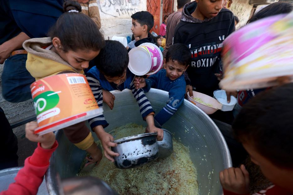 Bambini riempiono contenitori di cibo offerto da una Ong nella cittadina meridionale di Rafah