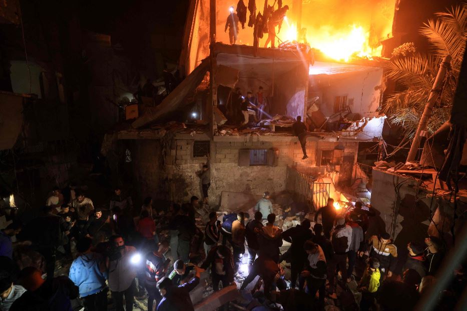 La ricerca delle vittime in un edificio in fiamme dopo un raid israeliano notturno su Rafah