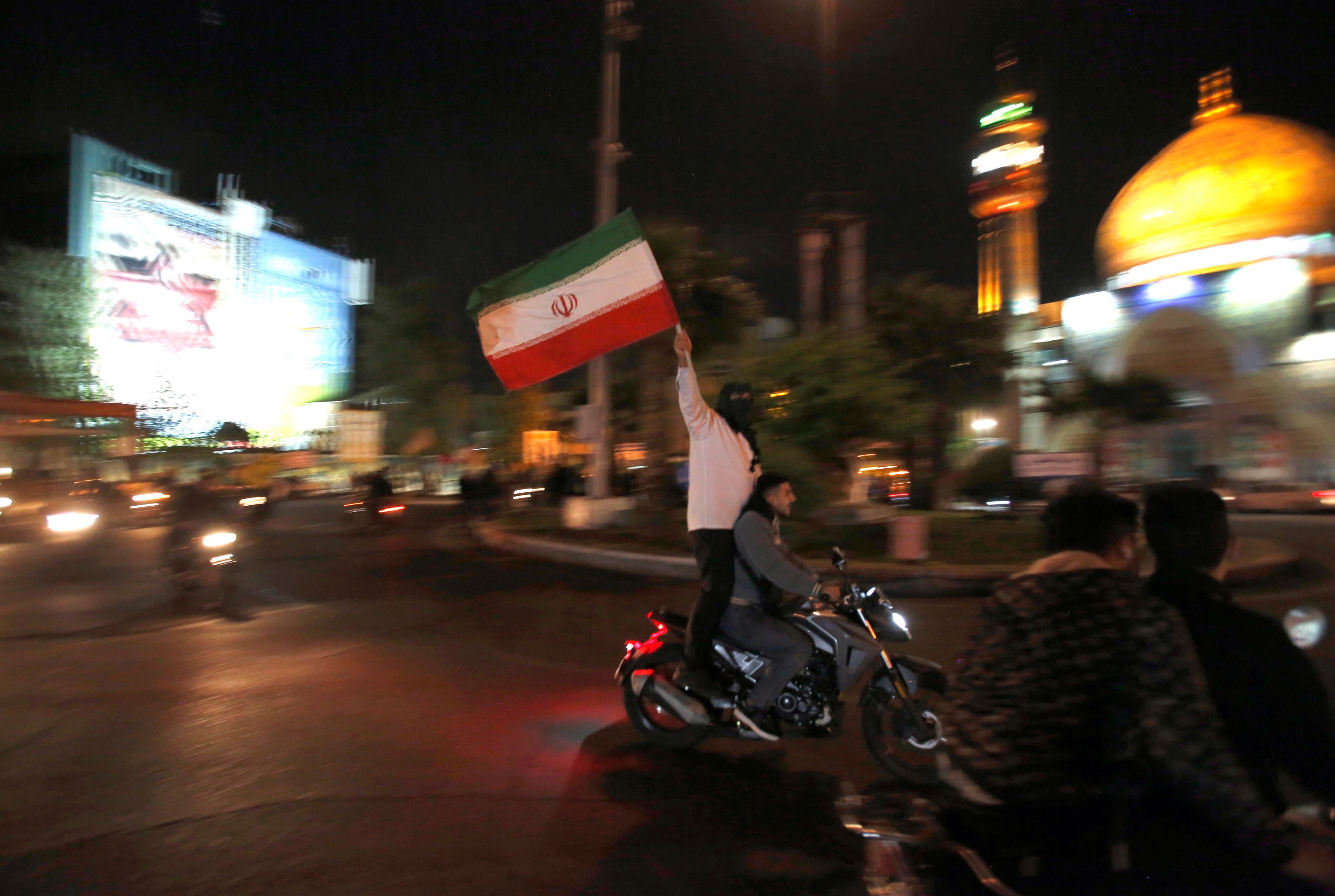 Ragazzi sventolano la bandiera iraniana durante la manifestazione anti-israeliana in piazza Palestina a Teheran scattata subito dopo l'attacco. Alba del 14 aprile 2024.