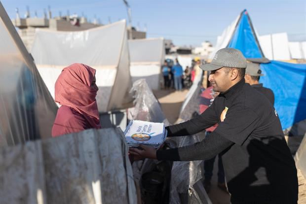 La consegna di pasti pronti in una tendopoli di sfollati