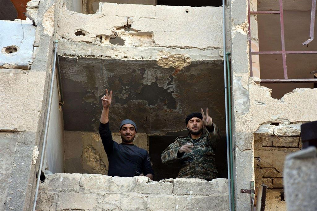 Soldati dell'esercito siriano fanno segno di vittoria dai quartieri conquistati (Ansa)