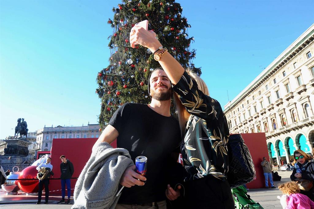 Un selfie in piazza Duomo davanti all'albero di Natale. Senza cappotto (Fotogramma)