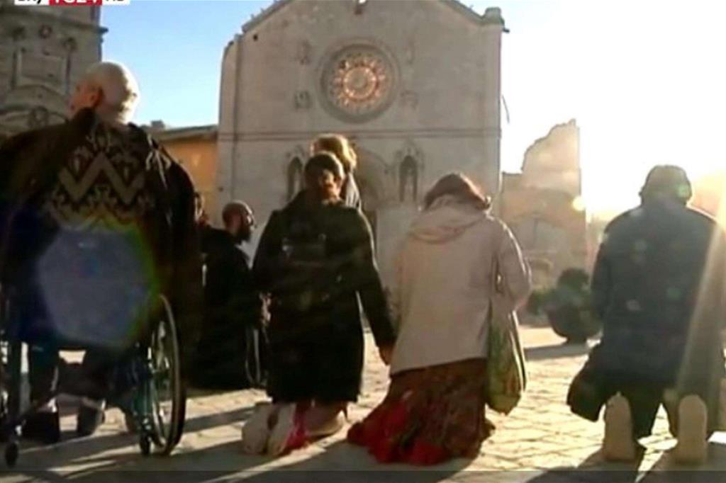 Fedeli e religiosi pregano di fronte alla basilica di San Benedetto sventrata dalla scosssa di terremoto del 30 ottobre (Ansa web)