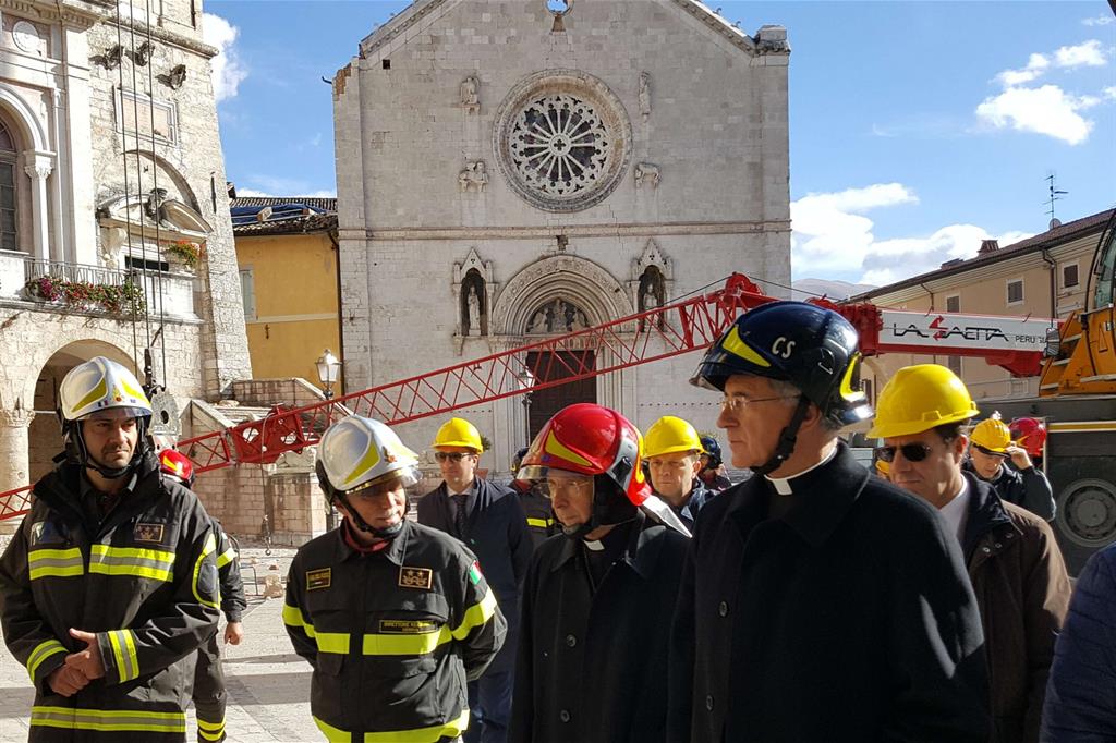 Bagnasco davanti alla facciata della Basilica di San Benedetto, crollata dopo il terremoto.